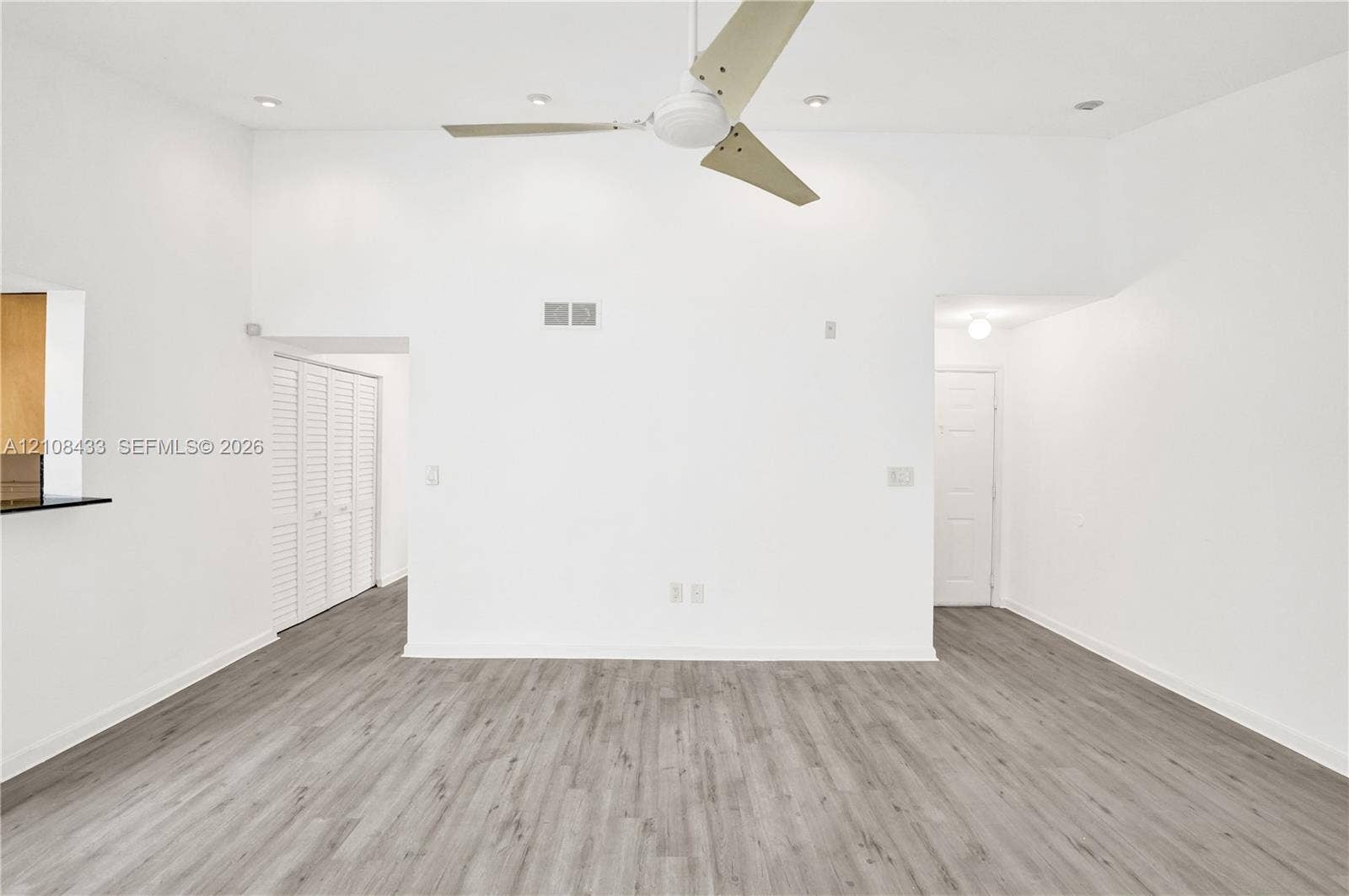 2300 NW 33rd Street, #911, Oakland Park, FL 33309 High ceilings featuring a central ceiling fan, recessed lighting, wood-finish flooring, and white louvered closet doors