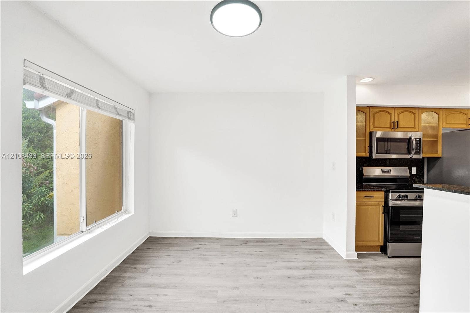 2300 NW 33rd Street, #911, Oakland Park, FL 33309 Wood-finish flooring, large sliding window, recessed lighting, and built-in cabinetry featuring stone countertops and stainless steel appliances