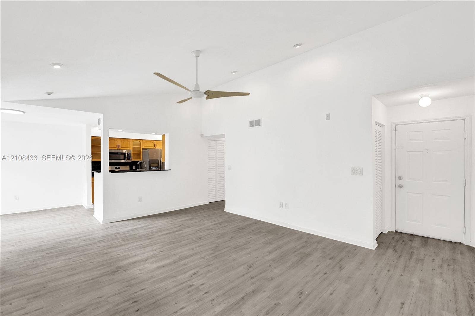2300 NW 33rd Street, #911, Oakland Park, FL 33309 Vaulted ceilings, wood-finish flooring, ceiling fan with light fixture, recessed lighting, and pass-through counter opening to kitchen