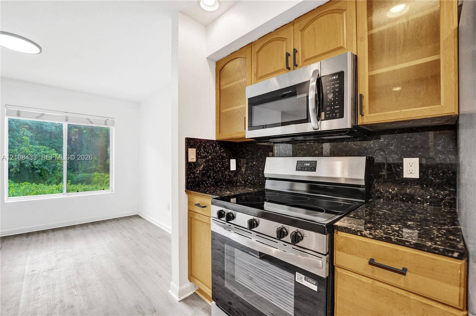 2300 NW 33rd Street, #911, Oakland Park, FL 33309 Kitchen featuring wood cabinetry, stainless steel appliances, dark stone countertops, and wood-finish flooring