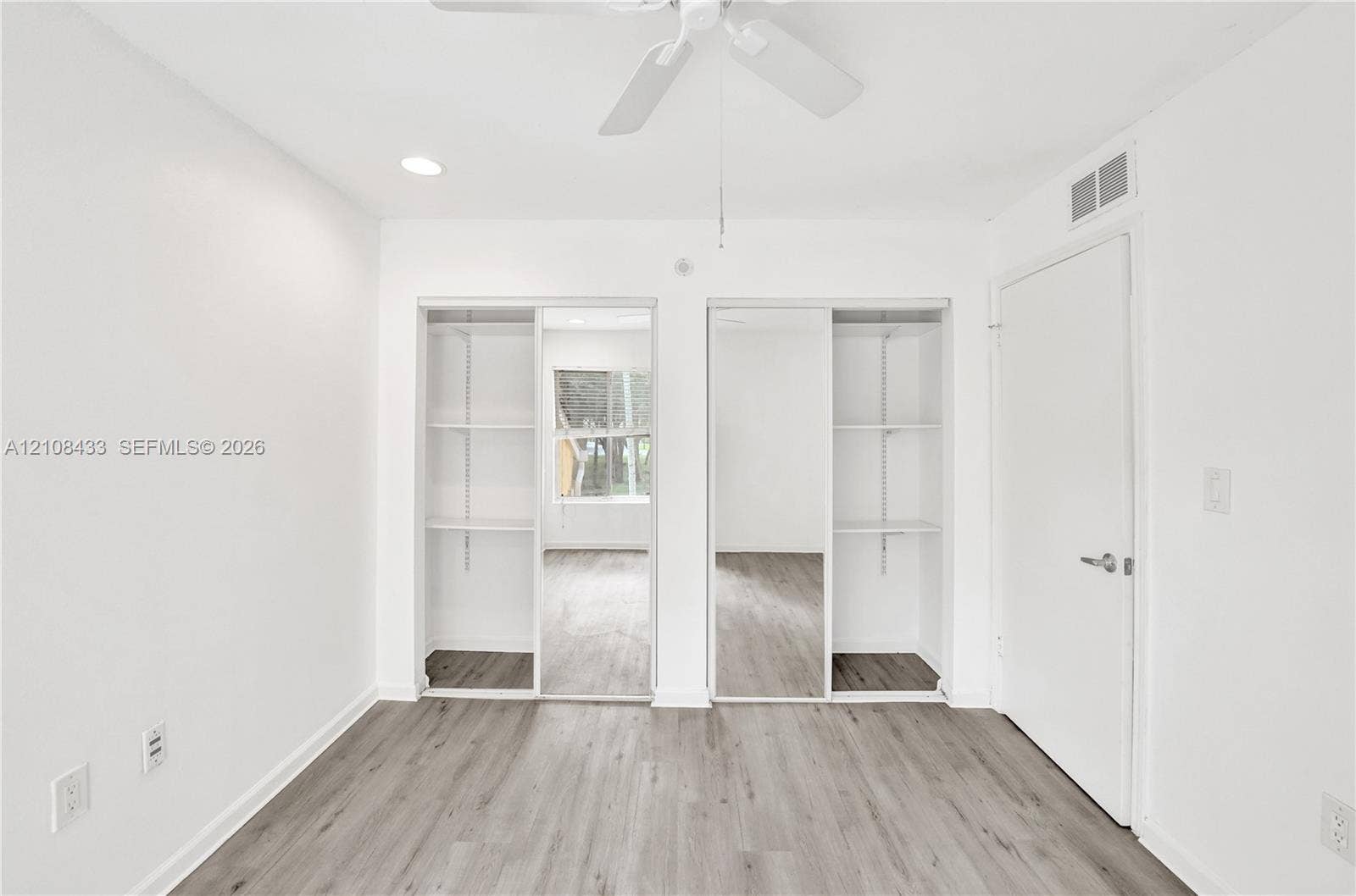 2300 NW 33rd Street, #911, Oakland Park, FL 33309 Wood-finish flooring, dual closets with sliding mirrored doors, built-in shelving, and a ceiling fan