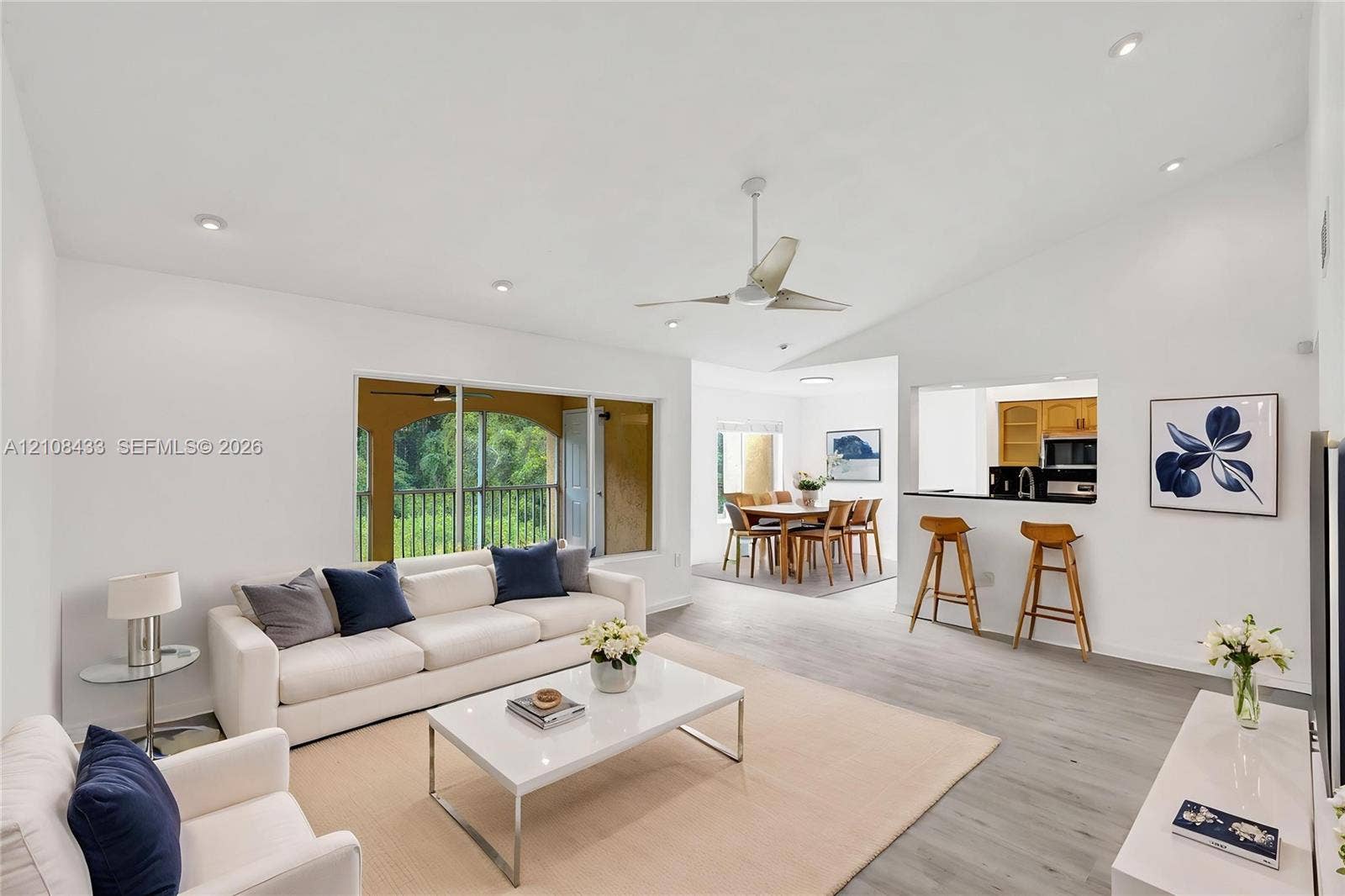 2300 NW 33rd Street, #911, Oakland Park, FL 33309 Living area featuring vaulted ceilings, recessed lighting, wood-finish flooring, a ceiling fan, and a pass-through opening to the kitchen