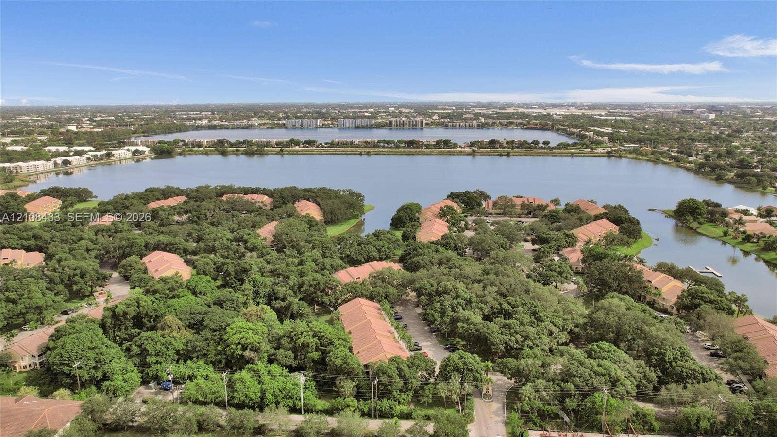 2300 NW 33rd Street, #911, Oakland Park, FL 33309 Aerial perspective of residential community featuring tile roofs, abundant mature tree canopy, paved streets, and expansive lake frontage