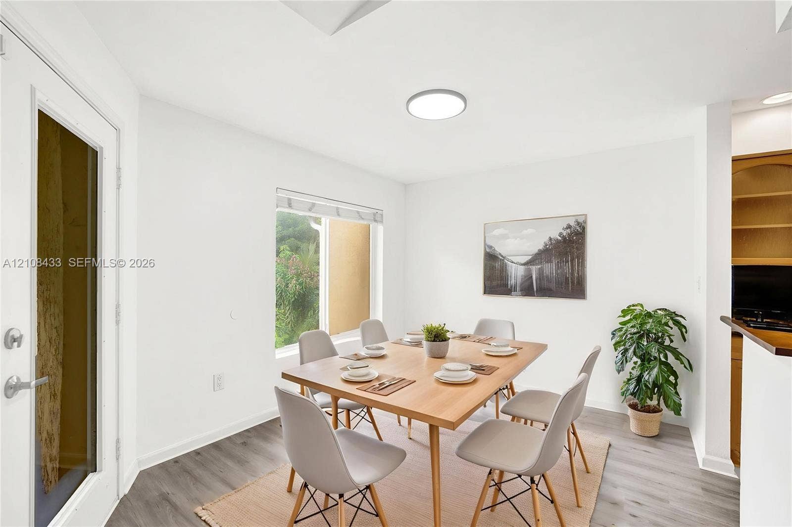 2300 NW 33rd Street, #911, Oakland Park, FL 33309 Dining area featuring wood-finish flooring, a flush-mount circular light fixture, a large window, and built-in wooden shelving