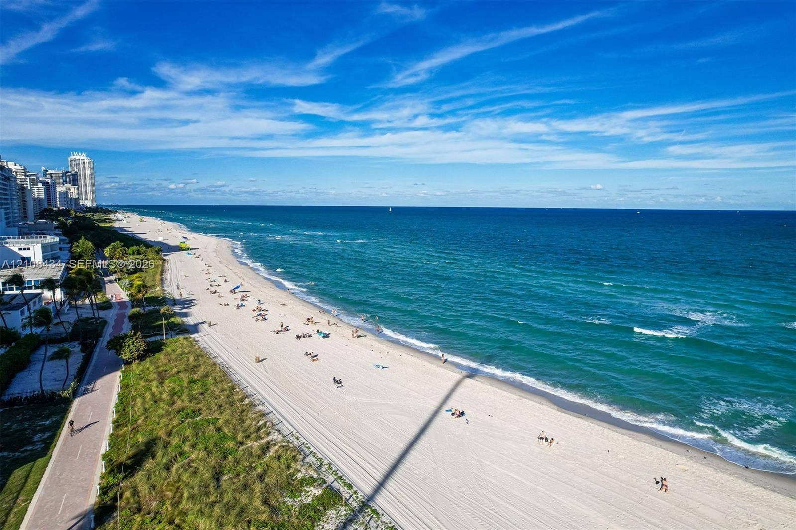 Miami Beach, FL 33140 Direct oceanfront location featuring a sandy beach, pedestrian walkway, and coastal vegetation