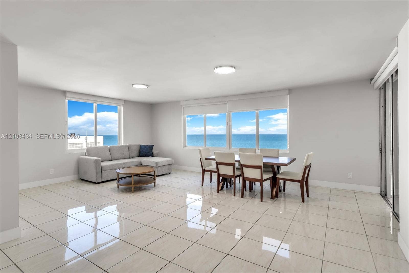 Miami Beach, FL 33140 Open-concept living space featuring high-gloss tile flooring, floor-to-ceiling windows, and panoramic ocean water scenery