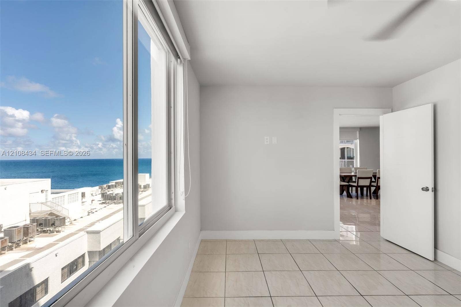 Miami Beach, FL 33140 Large-format windows providing ocean scenery, neutral wall finishes, tile flooring, and a solid-core interior door
