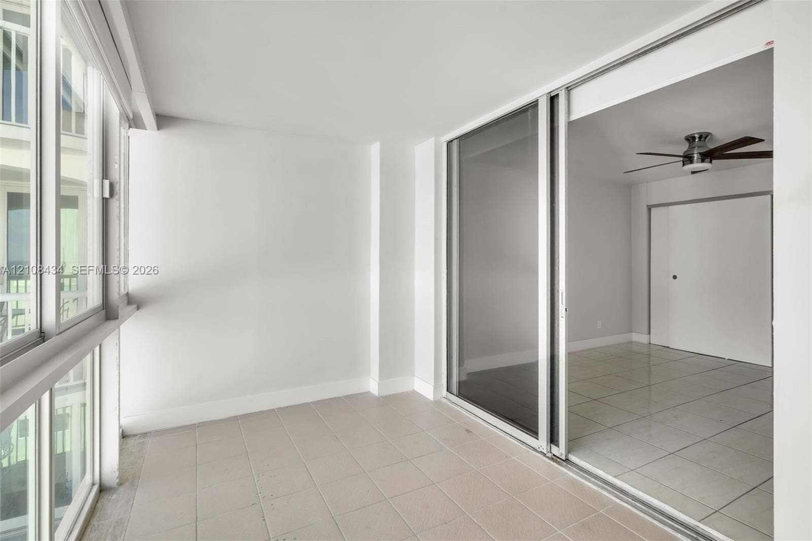 Miami Beach, FL 33140 Enclosed sunroom featuring expansive multi-pane windows, large-format tile flooring, and a sliding glass door system