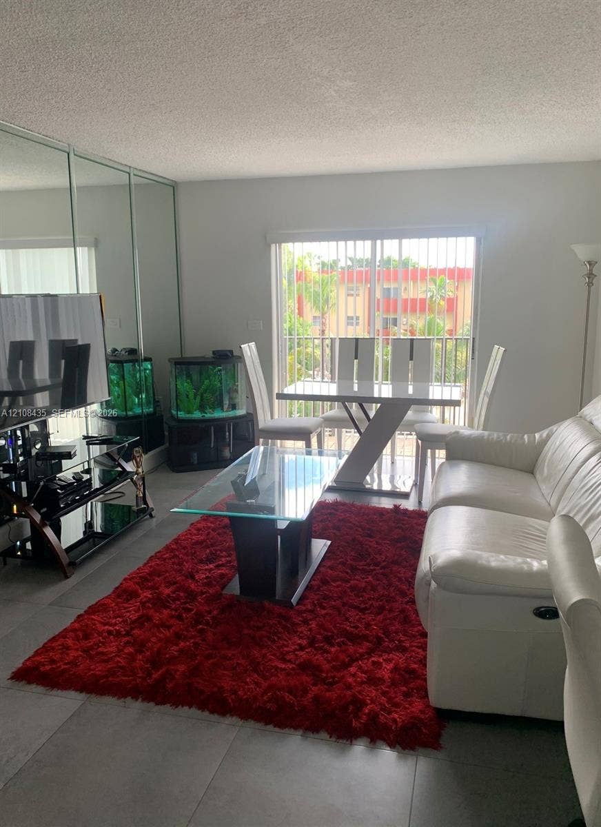 4275 S Tamiami Canal Drive, #2-314, Miami, Miami, FL 33126 Large format tile flooring, floor-to-ceiling mirrored wall paneling, and sliding glass doors with access to an exterior balcony