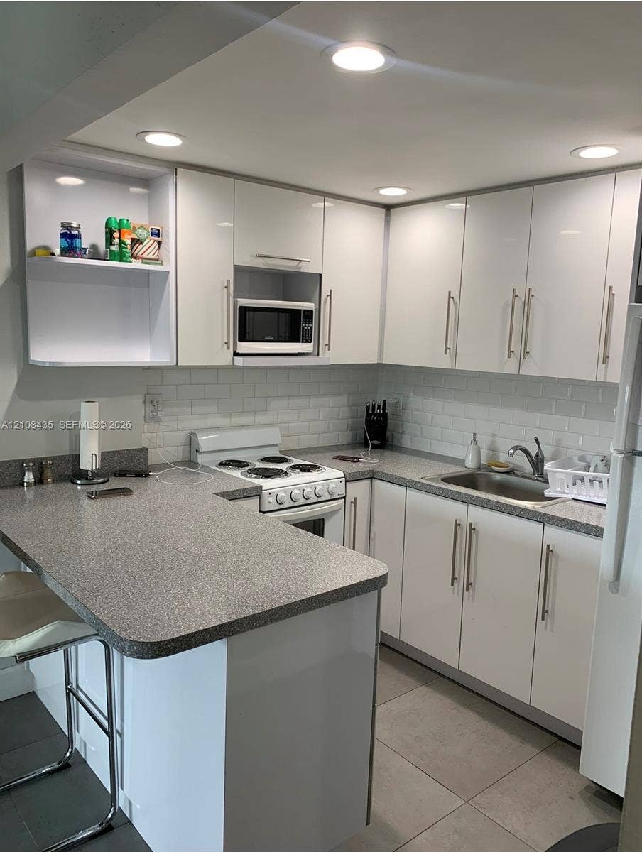 4275 S Tamiami Canal Drive, #2-314, Miami, Miami, FL 33126 Kitchen featuring white cabinetry, subway tile backsplash, solid-surface countertops, integrated lighting, and tile flooring