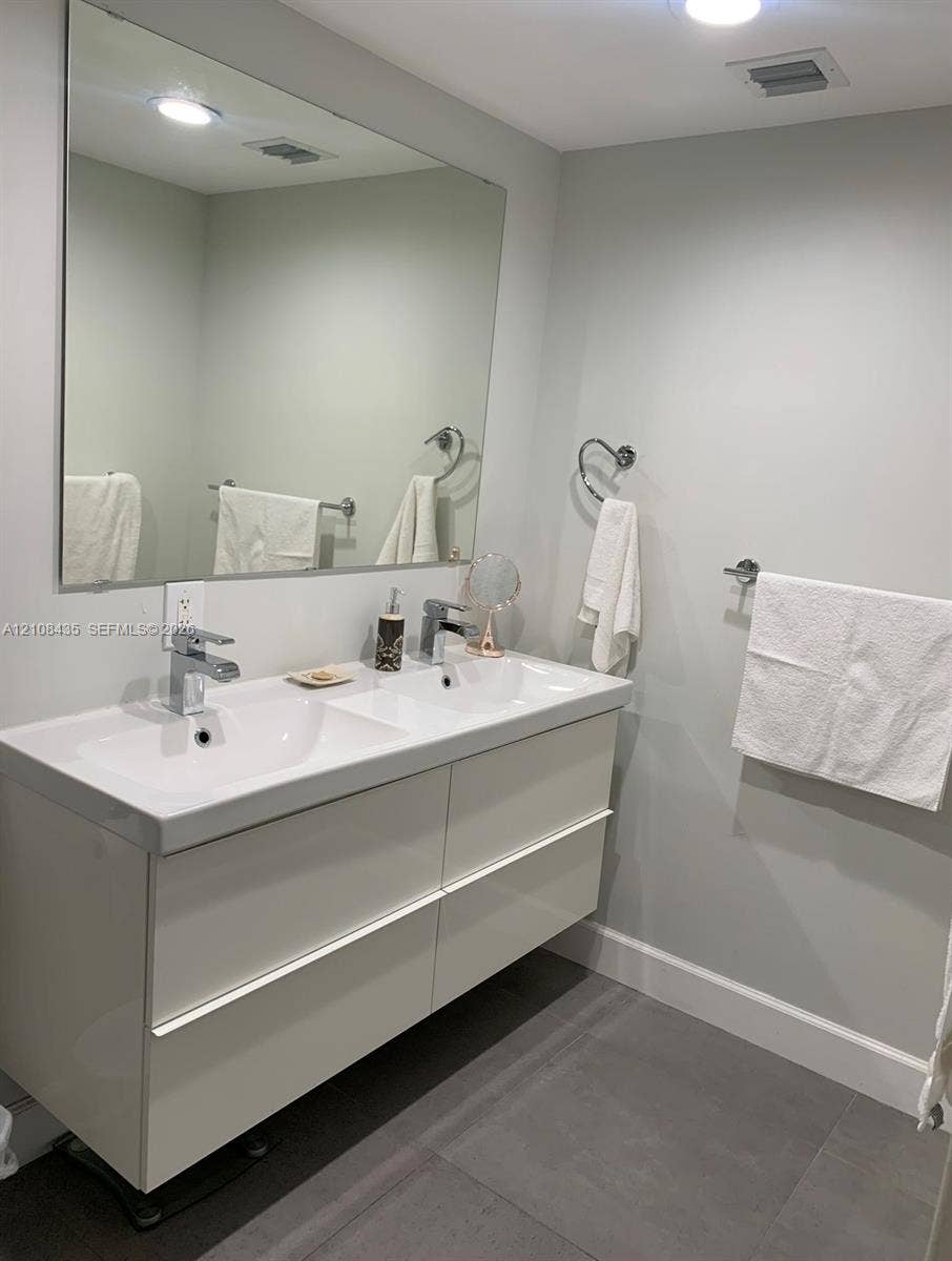 4275 S Tamiami Canal Drive, #2-314, Miami, Miami, FL 33126 Floating double vanity with integrated dual sinks, polished chrome faucets, large wall-mounted mirror, and tile flooring