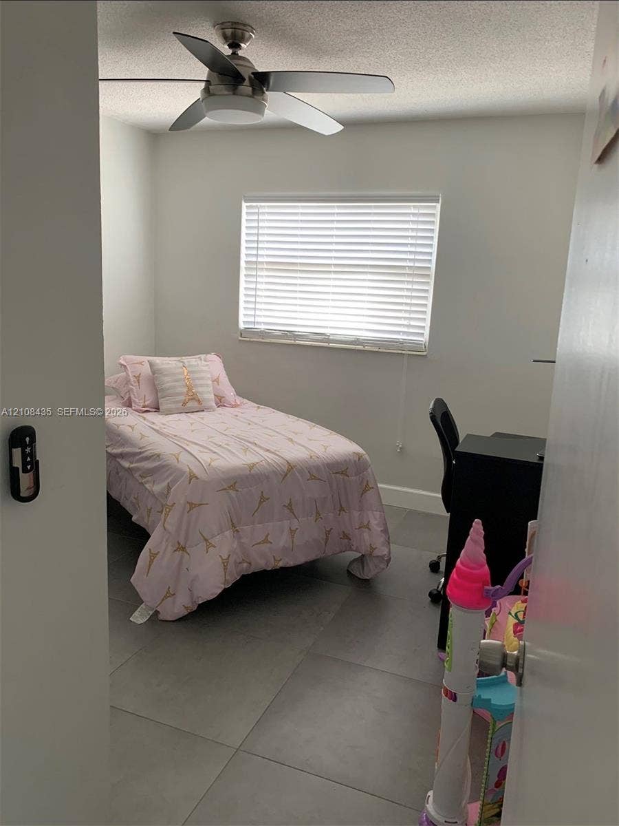 4275 S Tamiami Canal Drive, #2-314, Miami, Miami, FL 33126 Neutral-toned room featuring large-format ceramic floor tiling, a multi-speed ceiling fan with integrated light fixture, and horizontal window blinds