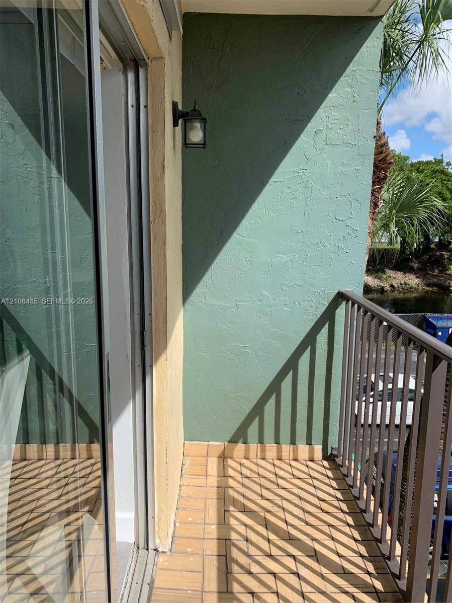 4275 S Tamiami Canal Drive, #2-314, Miami, Miami, FL 33126 Private balcony featuring textured stucco walls, tiled flooring, metal railing, and a wall-mounted light fixture