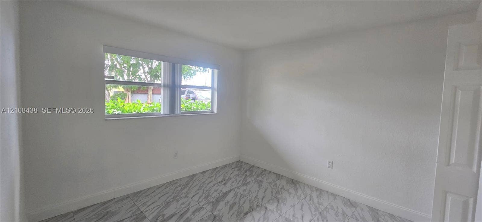 7320 NW 85th Court, #102, Tamarac, FL 33321 Interior space featuring light-colored tile flooring, smooth neutral wall finishes, and a single-pane horizontal window with integrated blinds