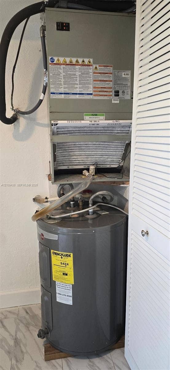 7320 NW 85th Court, #102, Tamarac, FL 33321 Vertical HVAC air handler unit paired with a gray cylindrical water heater, featuring louvered bi-fold closet doors and stone-finish flooring