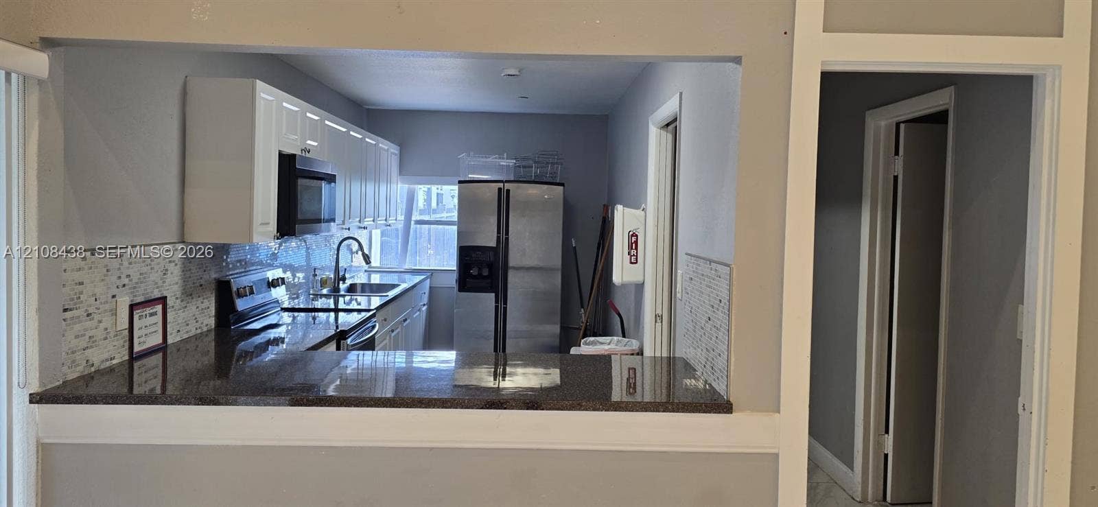 7320 NW 85th Court, #102, Tamarac, FL 33321 Kitchen featuring white cabinetry, dark stone-finish countertops, stainless steel appliances, and a tiled backsplash