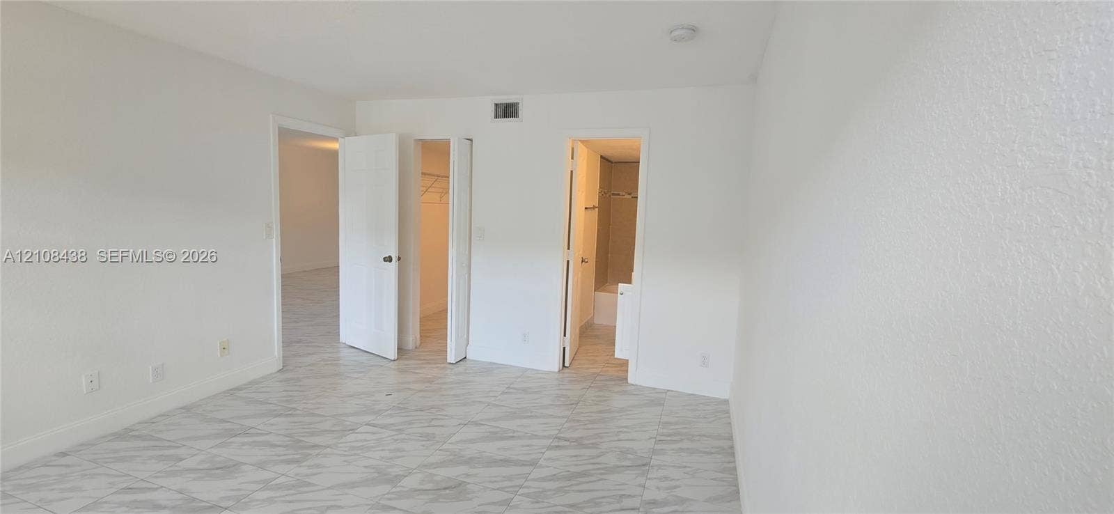 7320 NW 85th Court, #102, Tamarac, FL 33321 Interior space featuring large-format tile flooring with a neutral veined pattern, multiple closet entries, and a ceiling-mounted light fixture