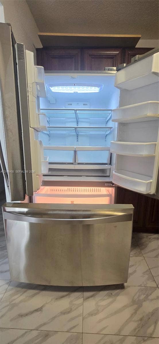 7320 NW 85th Court, #102, Tamarac, FL 33321 Stainless steel French-door refrigerator featuring an integrated bottom-mount freezer, adjustable interior shelving, and LED lighting