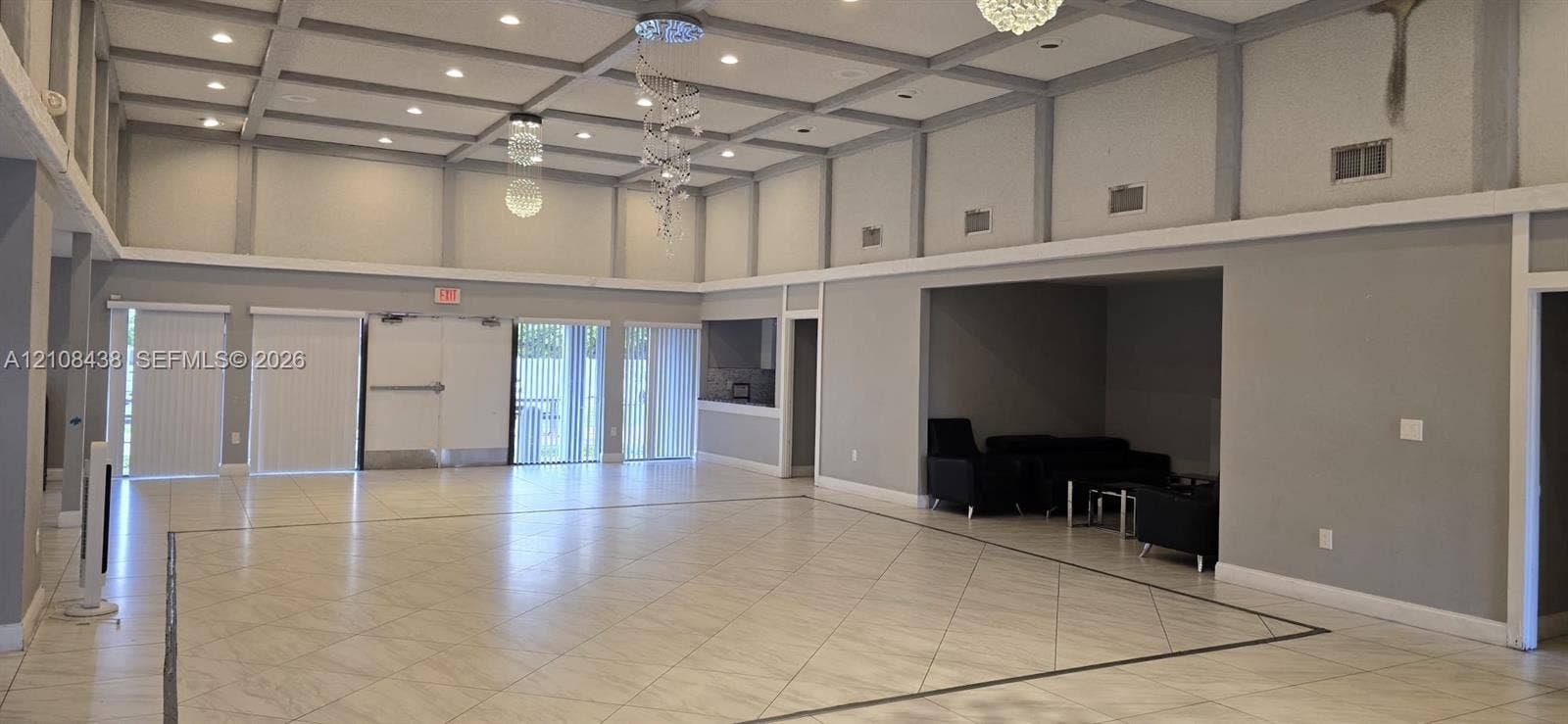 7320 NW 85th Court, #102, Tamarac, FL 33321 Large open-concept space featuring a coffered ceiling with recessed lighting, tile flooring, suspended decorative light fixtures, and glass sliding door access
