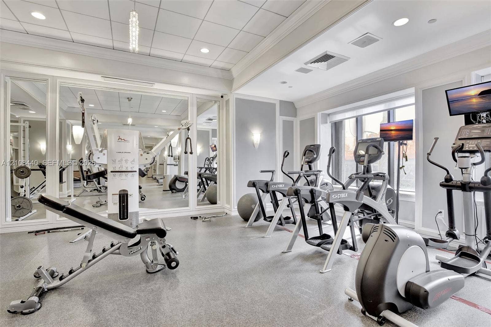 9801 Collins Avenue, #3T, Bal Harbour, Bal Harbour, FL 33154 Fitness space featuring floor-to-ceiling mirrors, a coffered ceiling with recessed lighting, wall-mounted sconces, and impact-resistant rubber flooring