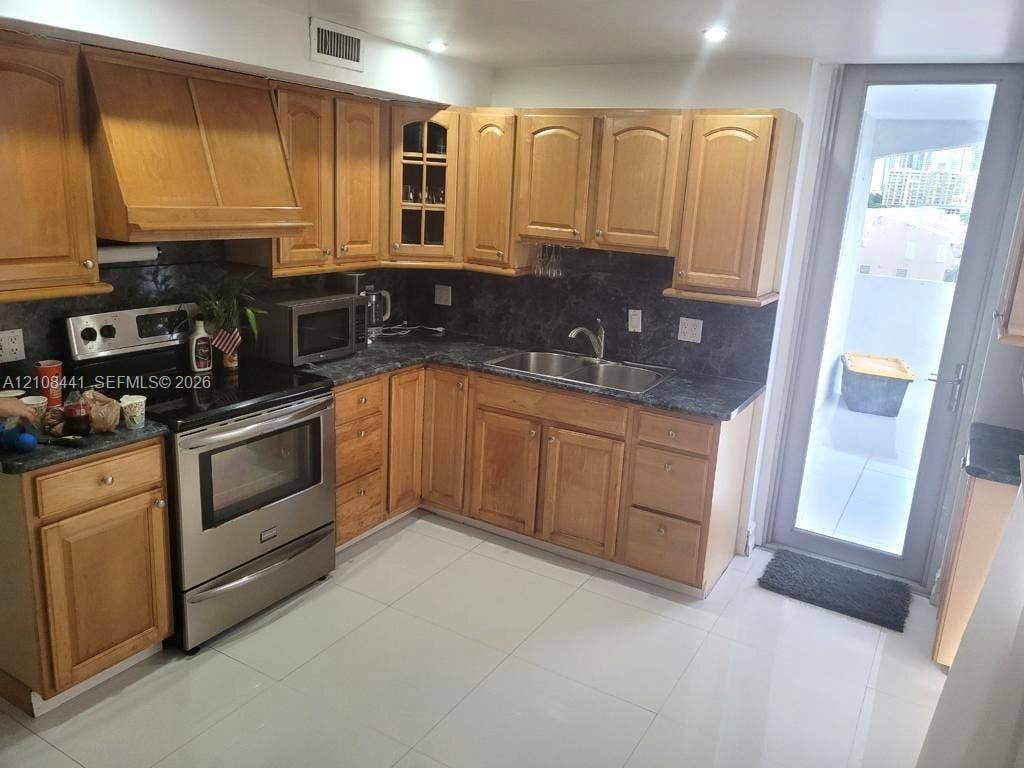 3703 NE 166th Street, #401, North Miami Beach, North Miami Beach, FL 33160 Kitchen featuring wood cabinetry, stone-finish countertops, stainless steel range, double-basin sink, and tile flooring