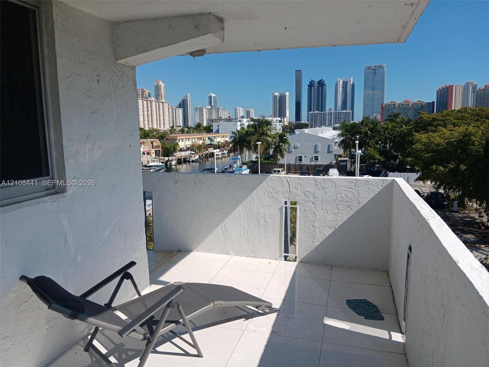 3703 NE 166th Street, #401, North Miami Beach, North Miami Beach, FL 33160 Private balcony featuring white tiled flooring, stucco walls, and an urban skyline backdrop
