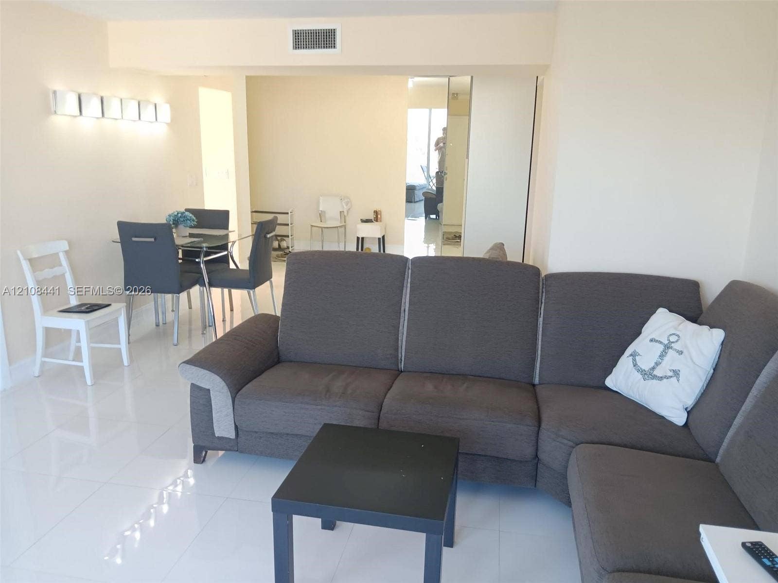 3703 NE 166th Street, #401, North Miami Beach, North Miami Beach, FL 33160 Large format tile flooring, wall-mounted multi-bulb light fixture, and mirrored closet doors