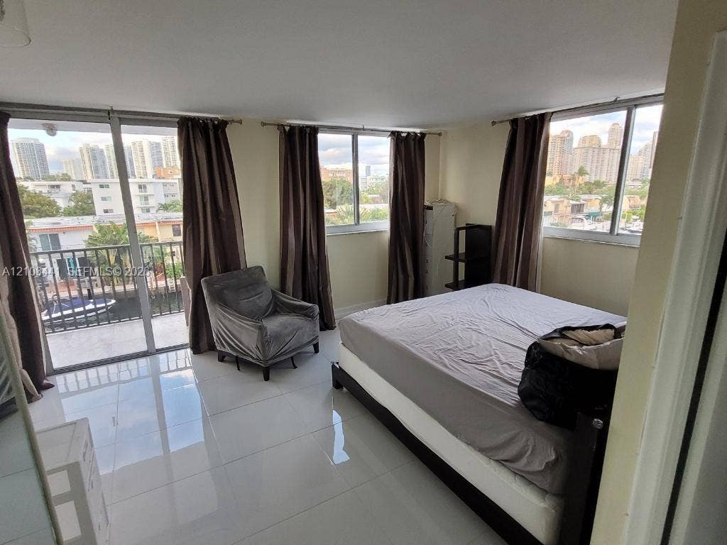 3703 NE 166th Street, #401, North Miami Beach, North Miami Beach, FL 33160 Spacious room featuring light-toned tile flooring, floor-to-ceiling windows, and access to a private balcony with a metal railing