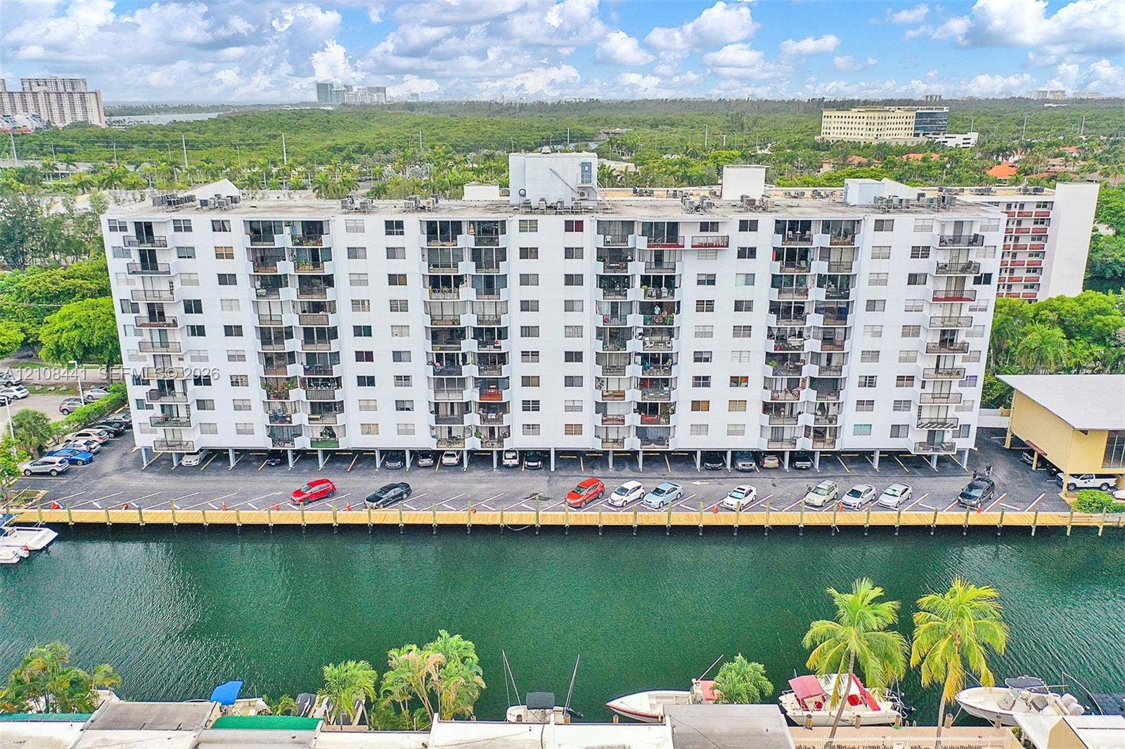 3703 NE 166th Street, #401, North Miami Beach, North Miami Beach, FL 33160 Multi-story residential building featuring private balconies, assigned surface parking, and a waterfront bulkhead with direct canal access