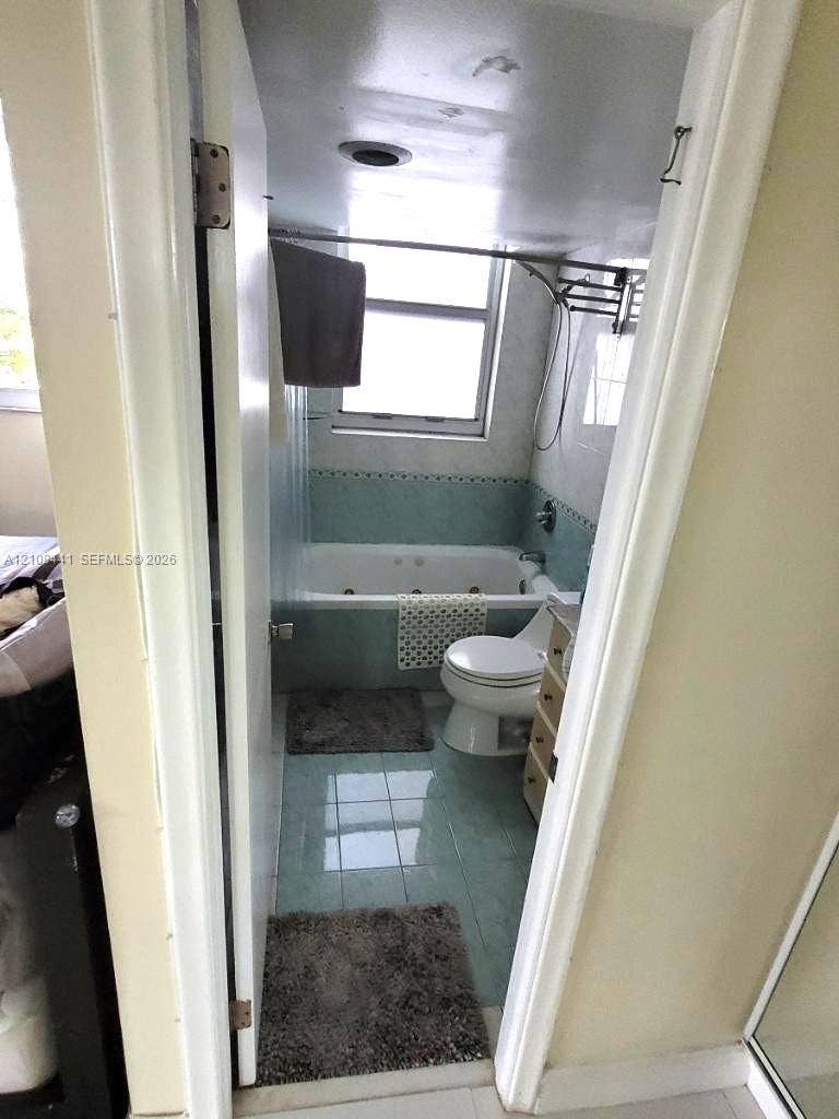 3703 NE 166th Street, #401, North Miami Beach, North Miami Beach, FL 33160 Jetted soaking tub with tile surround, porcelain toilet, and light-toned tile flooring