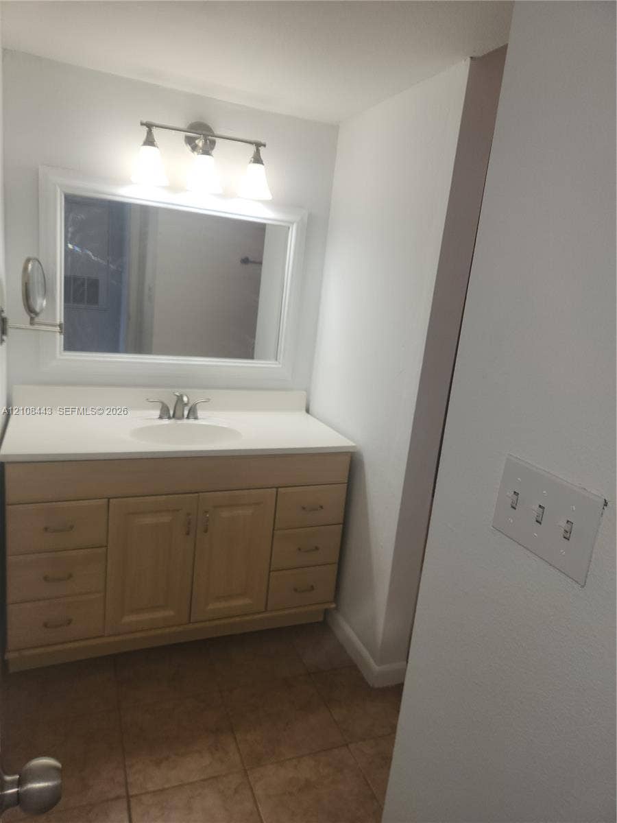 4018 NW 87th Avenue, #4018, Sunrise, Sunrise, FL 33351 Light-toned wood vanity with ample drawer storage, integrated sink, large wall-mounted mirror, and three-light fixture over tile flooring
