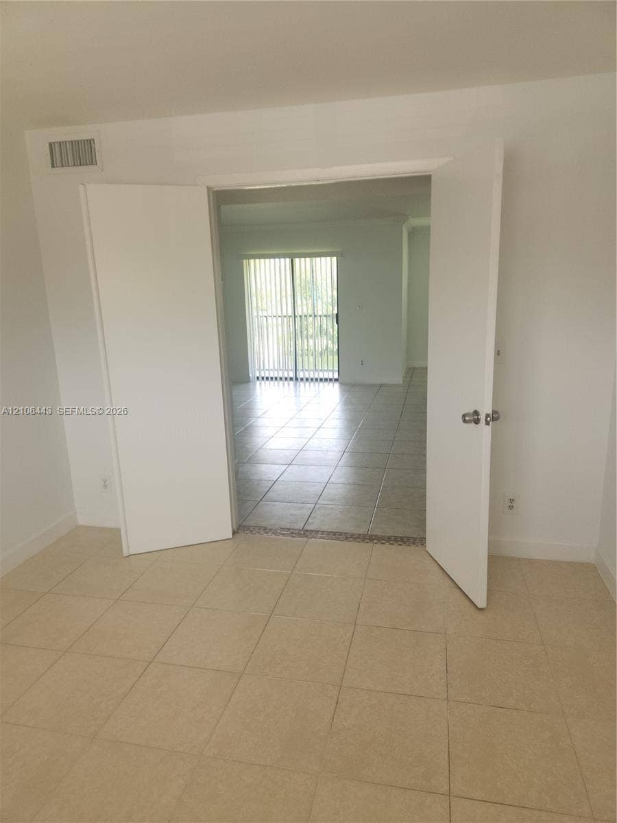 4018 NW 87th Avenue, #4018, Sunrise, Sunrise, FL 33351 Interior space featuring light-toned ceramic tile flooring, white-painted double doors, and sliding glass balcony doors