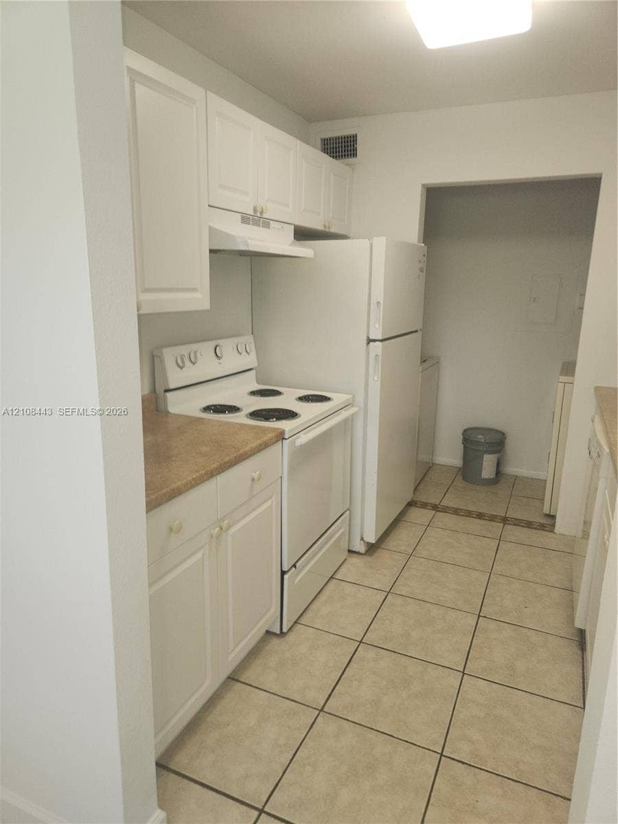 4018 NW 87th Avenue, #4018, Sunrise, Sunrise, FL 33351 Kitchen featuring white cabinetry, solid-surface countertops, tile flooring, and integrated white appliances