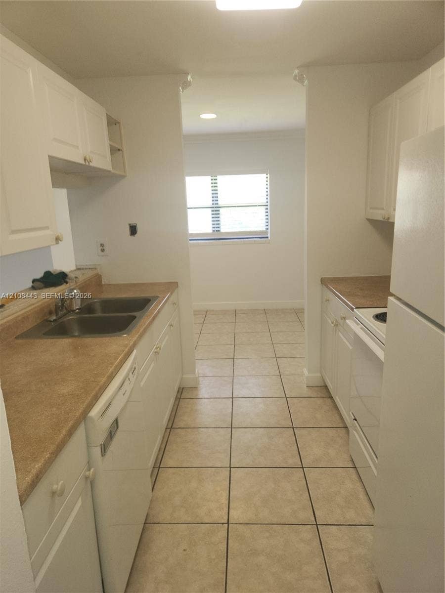4018 NW 87th Avenue, #4018, Sunrise, Sunrise, FL 33351 Kitchen featuring white cabinetry, solid-surface countertops, dual-basin stainless steel sink, and ceramic tile flooring