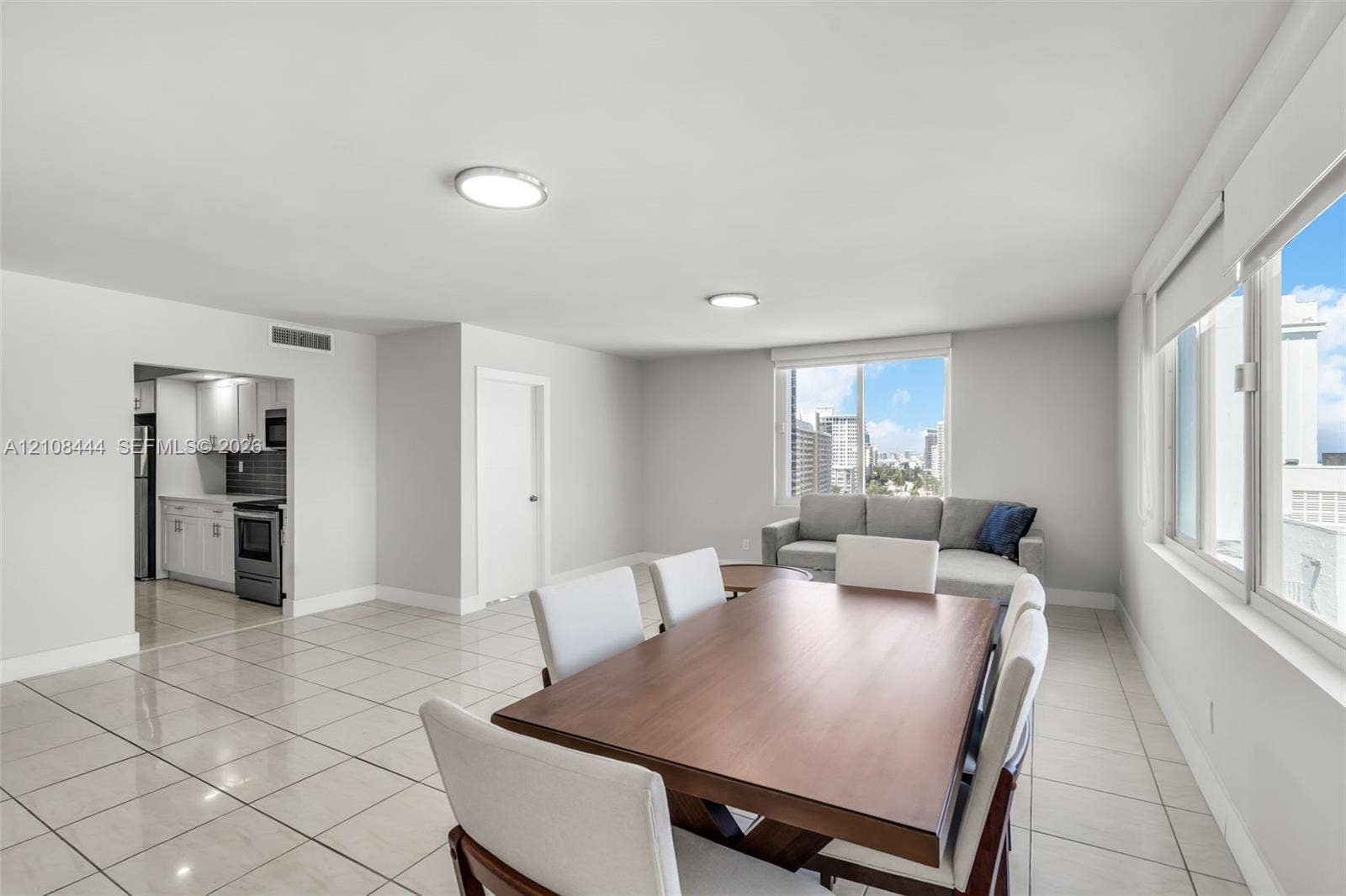 Open-concept interior featuring large-format ceramic tile flooring, neutral walls, recessed ceiling lighting, and expansive windows