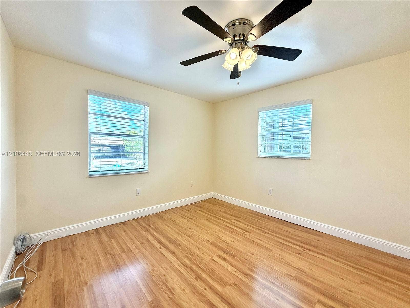 800 W 81st Place, Hialeah, Hialeah, FL 33014 Bedroom 2 featuring wood-finish flooring, two windows with horizontal blinds, and a central ceiling fan with multi-light fixture