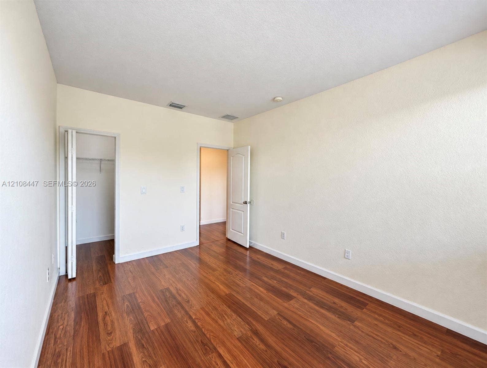 Interior space featuring wood-finish flooring, neutral wall tones, a multi-panel interior door, and a built-in closet with wire shelving