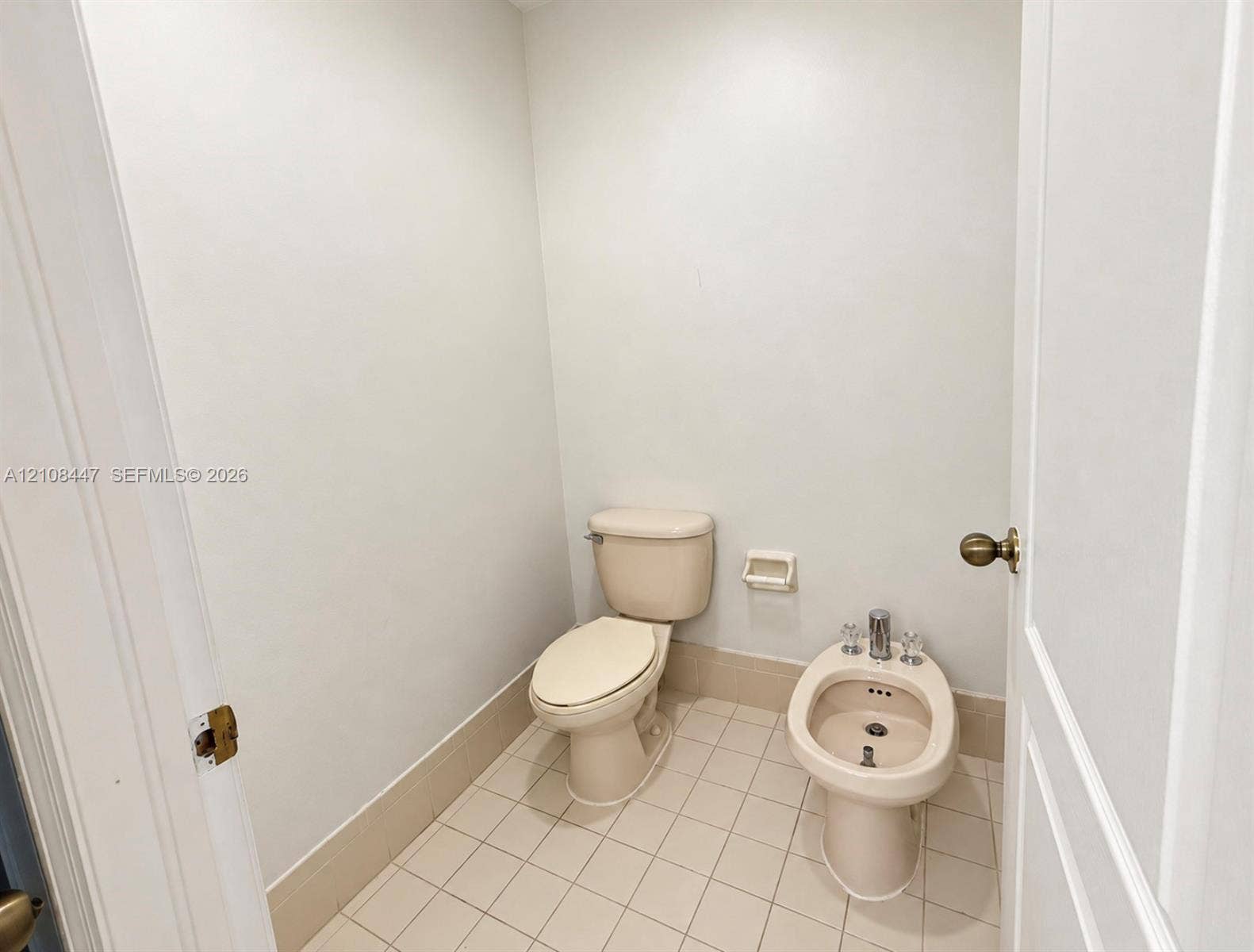 Restroom featuring a floor-mounted toilet, porcelain bidet with polished chrome faucet hardware, and neutral-tone tile flooring