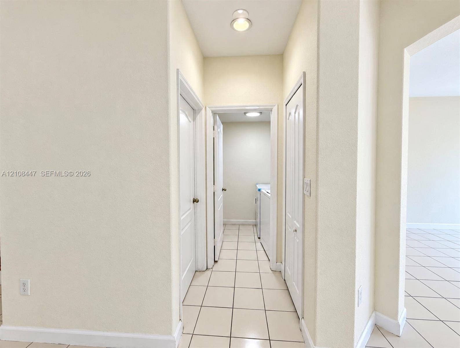 Neutral-toned interior hallway featuring ceramic tile flooring, multi-panel doors, and recessed lighting