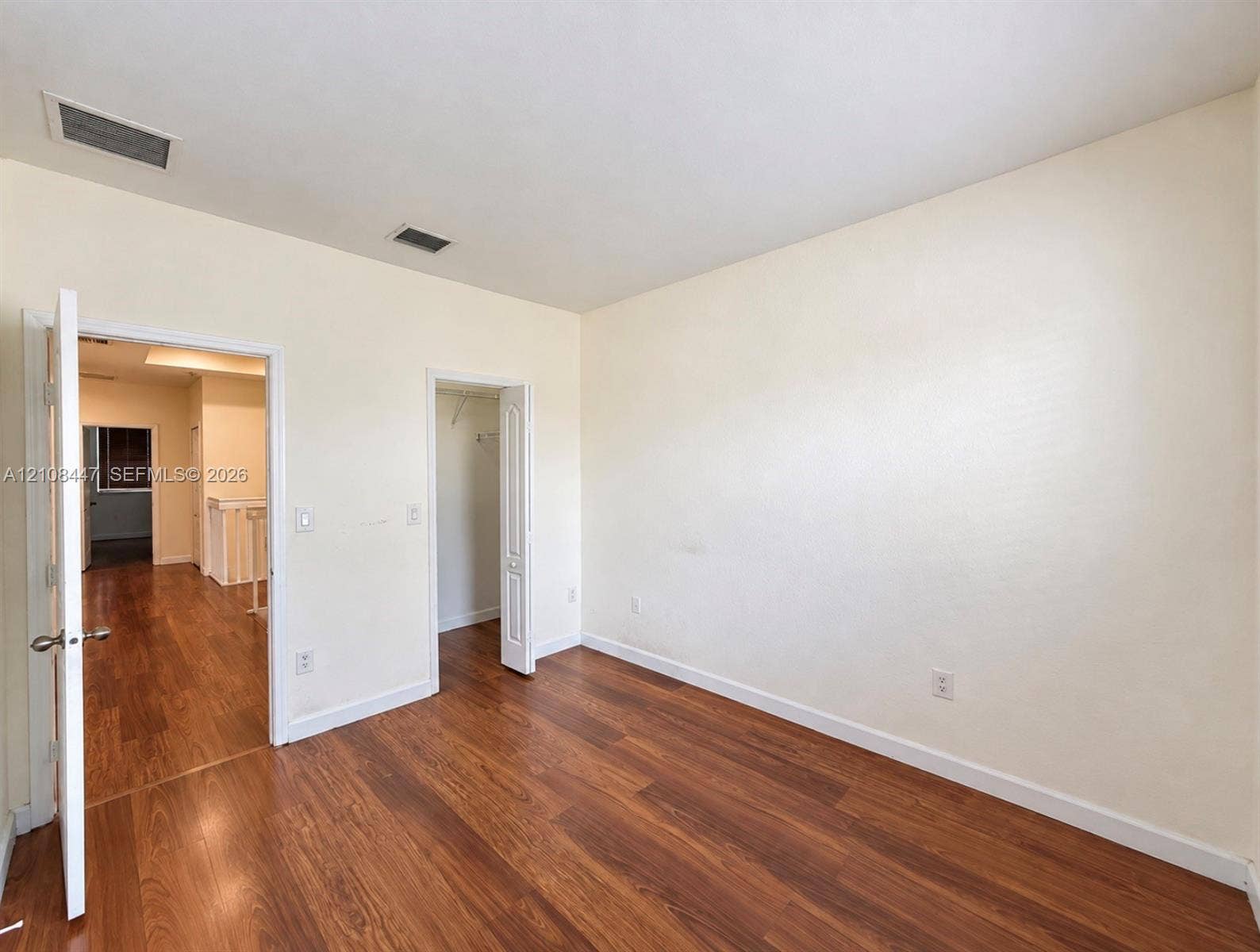 Room featuring wood-finish flooring, neutral wall tones, and a built-in closet with double-panel doors