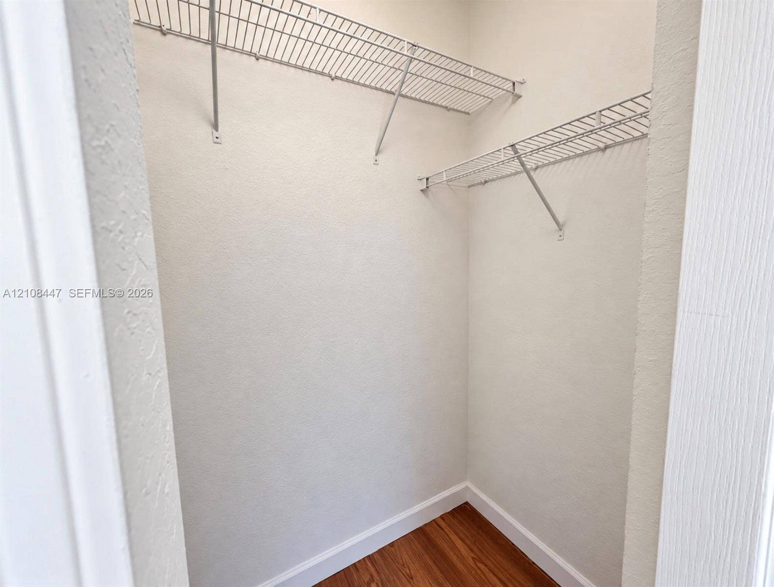 Reach-in closet featuring wood-finish flooring and tiered white wire shelving
