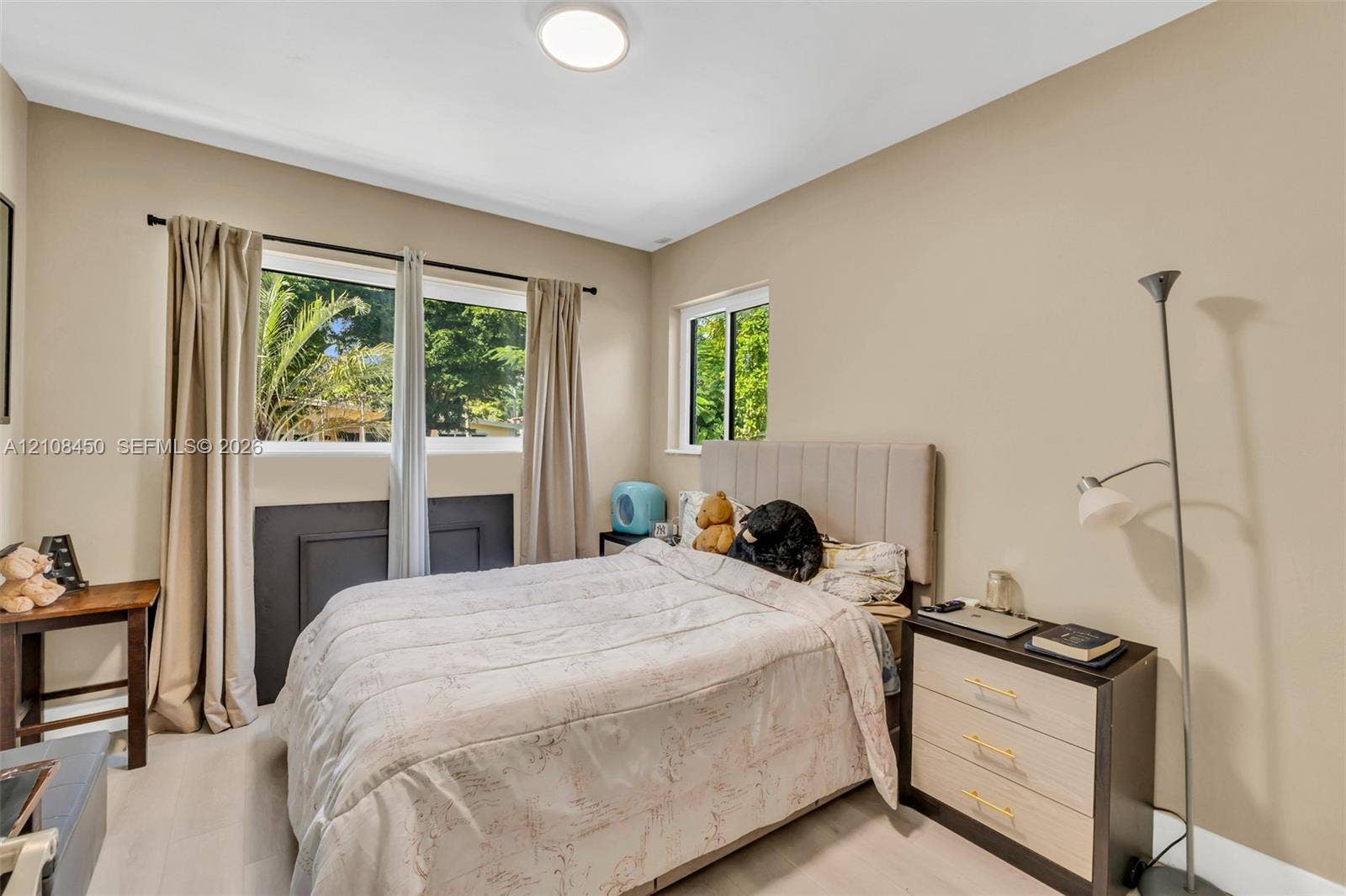 Neutral-toned room featuring a multi-pane sliding window, a single-pane sliding window, wood-finish flooring, and a flush-mount ceiling light