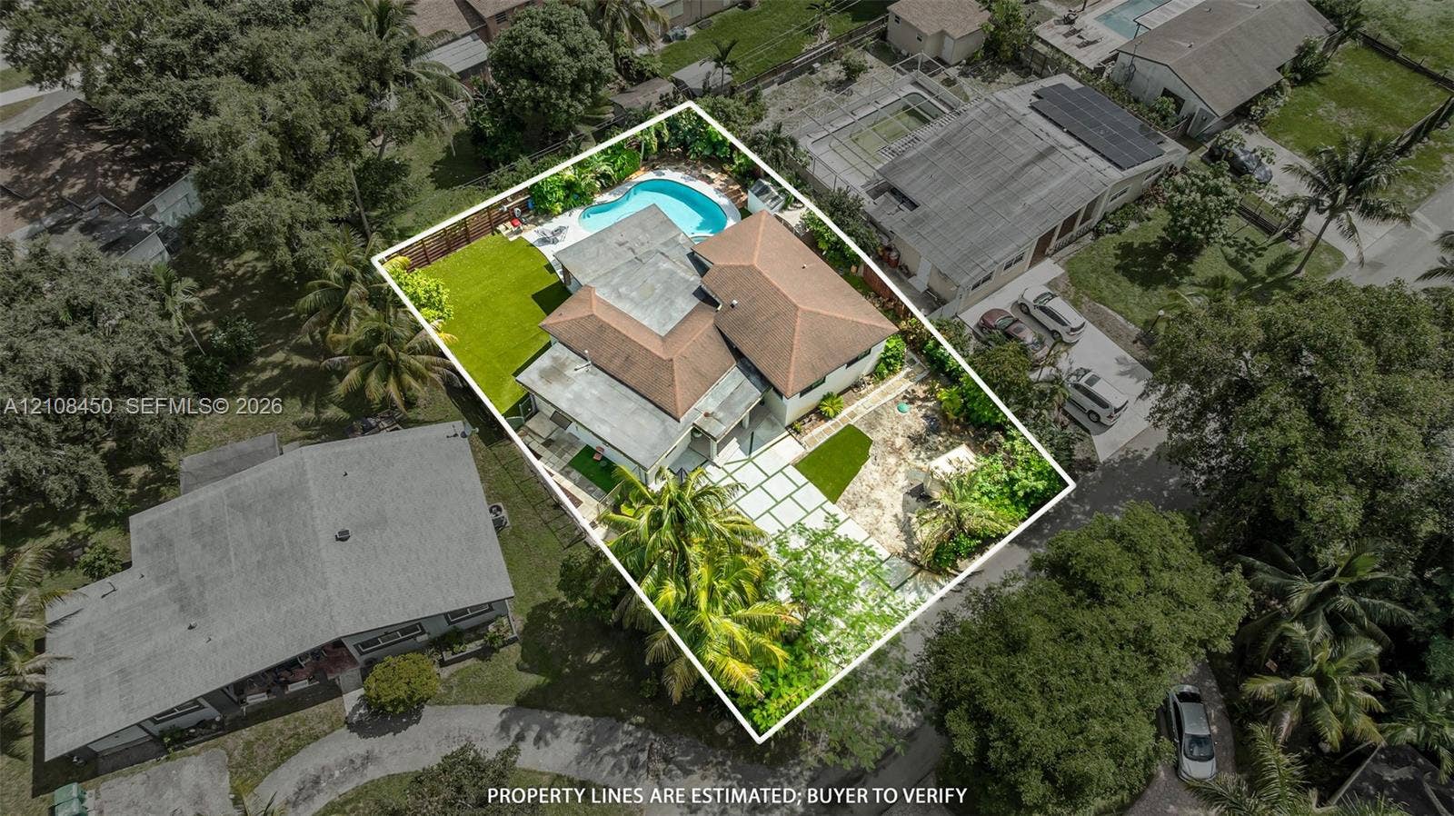 Aerial perspective featuring a multi-hipped roofline, in-ground swimming pool, fenced perimeter, and geometric paver driveway