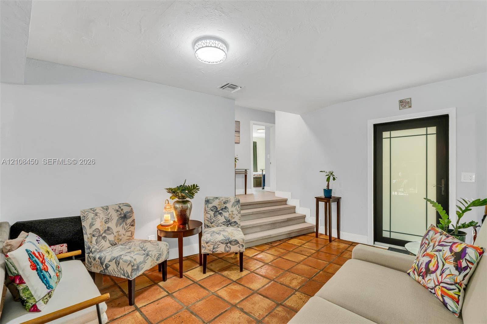Terra cotta tile flooring, glass-paneled exterior door, and multi-level floor plan featuring stepped elevation