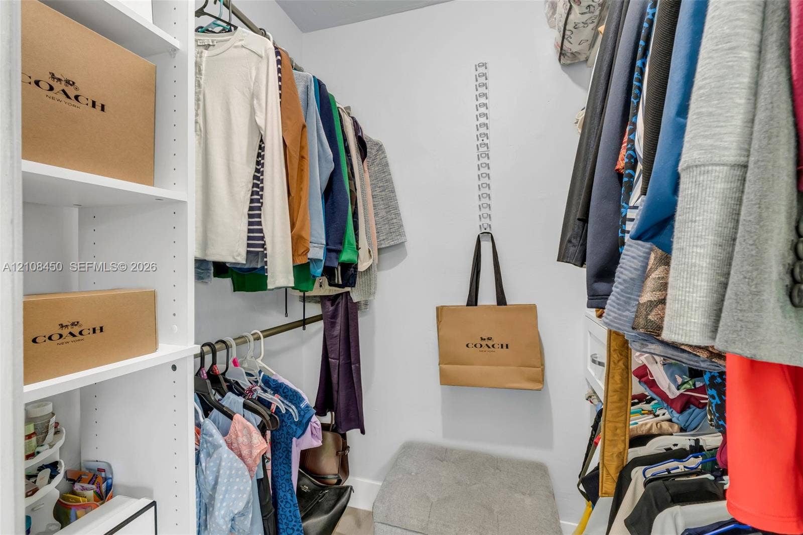Walk-in closet featuring white built-in shelving and multi-level metal hanging rods