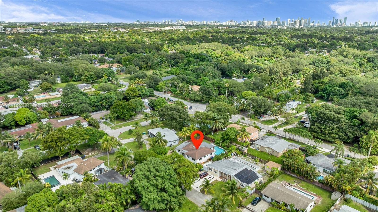 Aerial perspective of property featuring an inground swimming pool, concrete driveway, and expansive mature landscaping