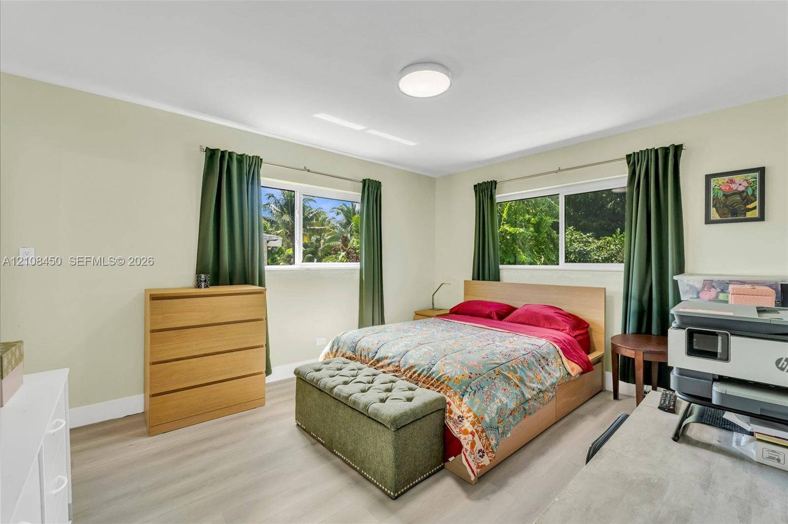 Bedroom featuring light wood-finish flooring, dual sliding windows, and a flush-mount ceiling light fixture