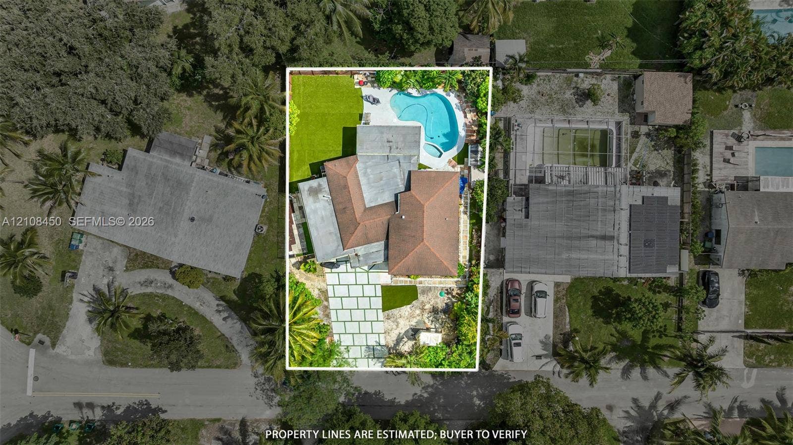 Aerial view featuring a paved driveway, hip-style roof, swimming pool, and manicured lawn
