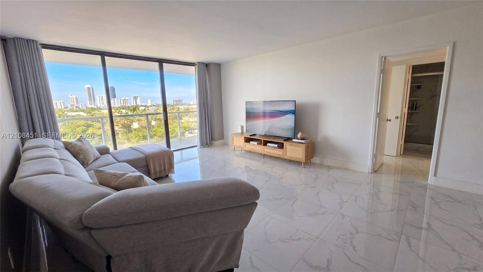 3701 N Country Club Drive, #701, Aventura, Aventura, FL 33180 Living area featuring large-format tile flooring, floor-to-ceiling glass sliding doors, and a private balcony with an expansive cityscape