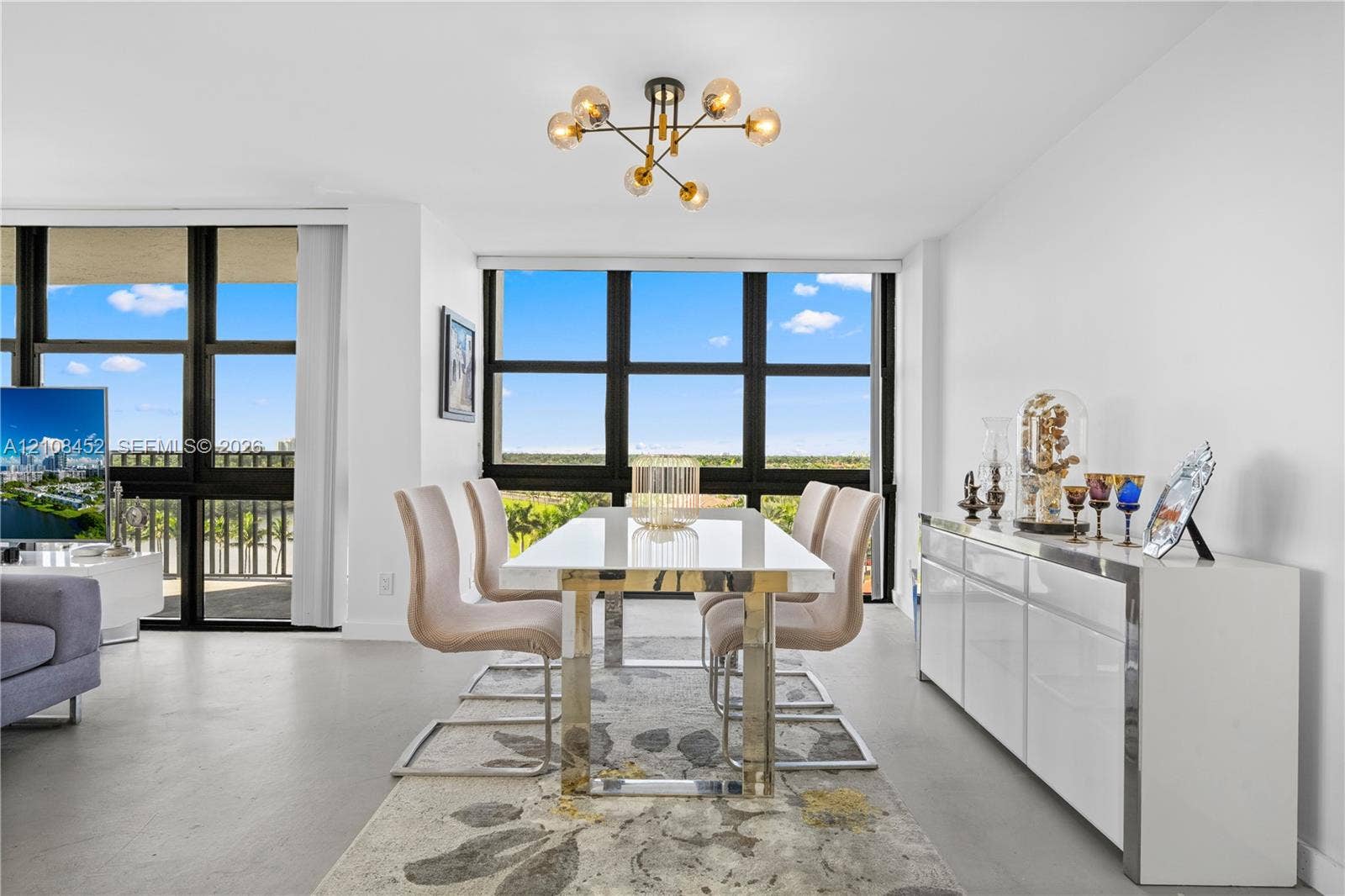 1000 Parkview Drive, #809, Hallandale Beach, FL 33009 Dining area featuring floor-to-ceiling windows with black framing, polished concrete flooring, and a multi-arm, modern sphere chandelier